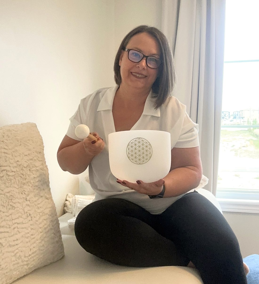 Alice Mosolo holding a crystal singing bowl in her Woodbridge studio
