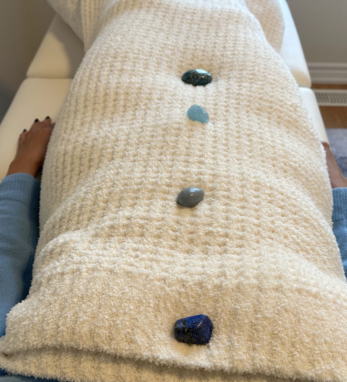 Crystals placed along a client resting under a soft blanket during a Reiki session